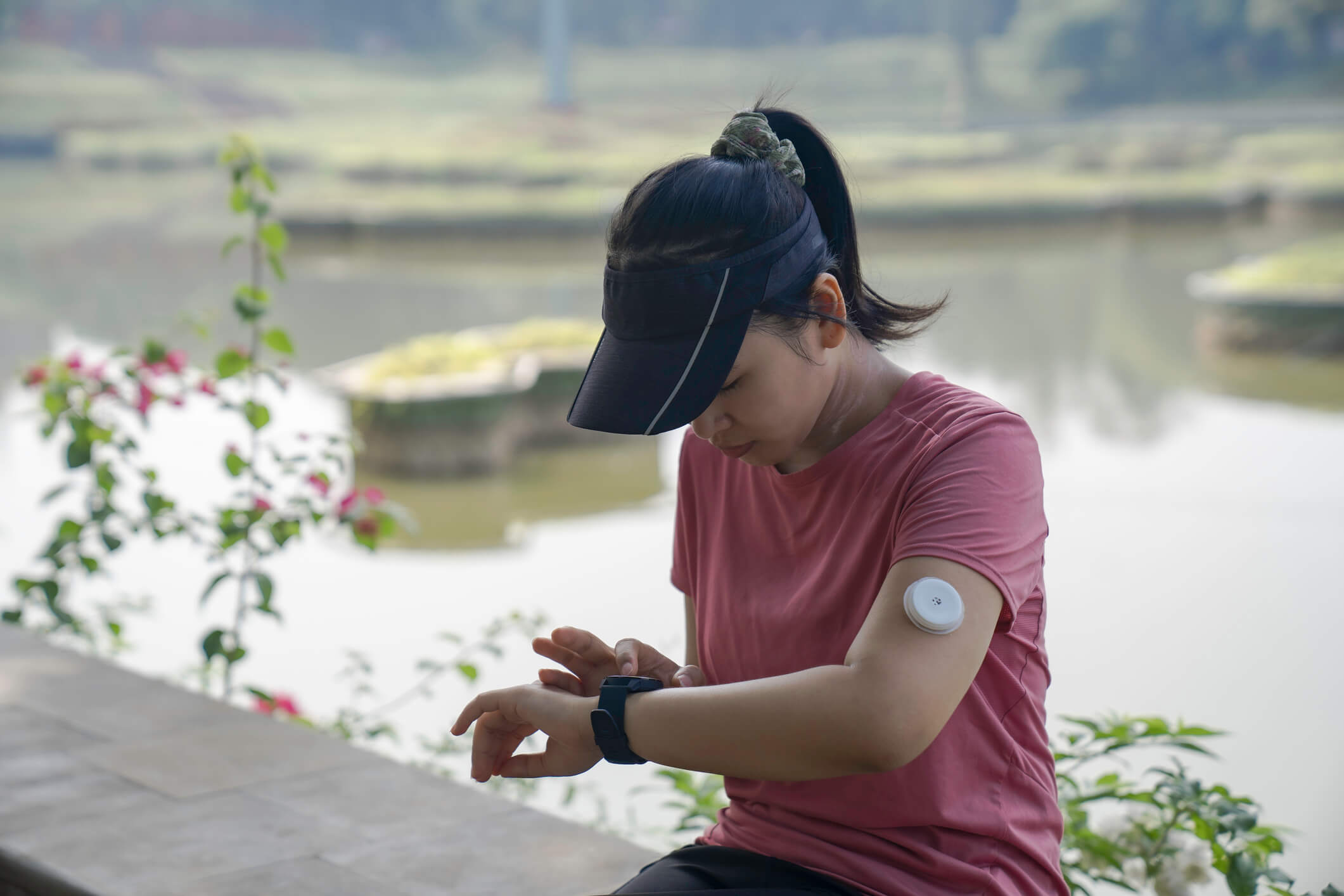 Young athletic woman wearing a continuous glucose monitor checking her watch.