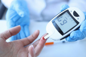 Doctor measuring patient's blood glucose with a sugar level monitor